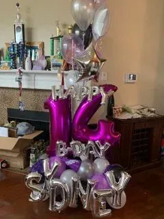 A bunch of balloons are sitting on the floor in a living room.
