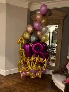 A bunch of balloons are sitting in a room next to a mirror.