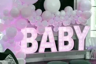 A room decorated with pink and white balloons and the word baby.