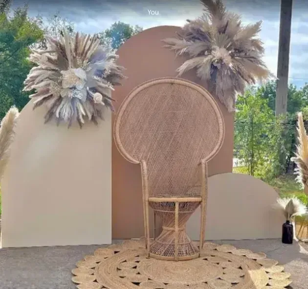 A wicker chair is sitting in front of a wall with feathers on it.