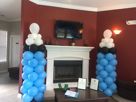 A living room with blue and white balloons in front of a fireplace