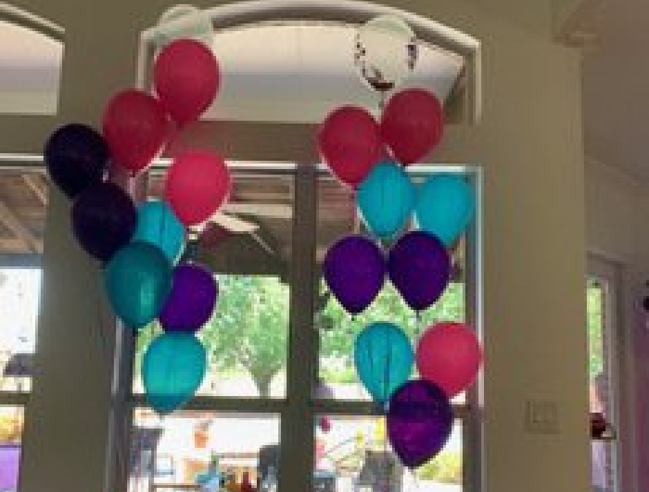 A bunch of balloons are hanging from the ceiling in a room.