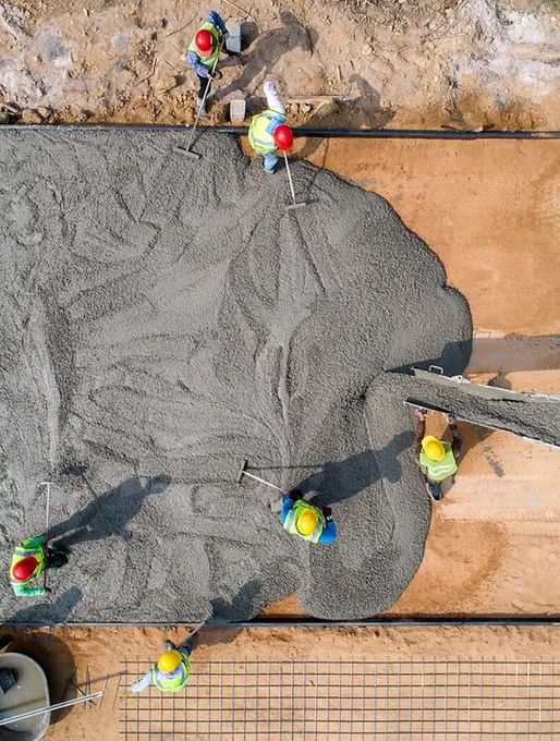 An aerial view of a group of construction workers pouring concrete.