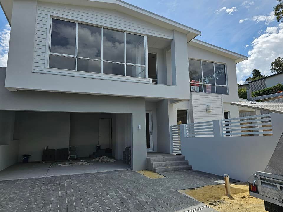 View of an exterior double-level light gray house, showcasing expert residential painting. View of an exterior double-level light gray house, showcasing expert residential painting.