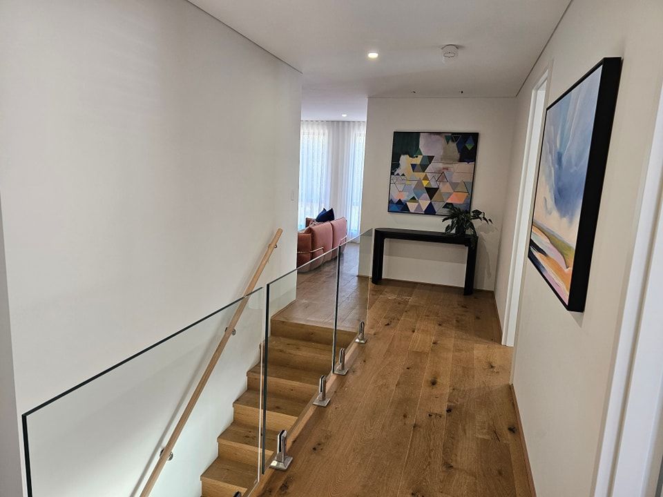 A hallway with stairs and a painting on the wall.