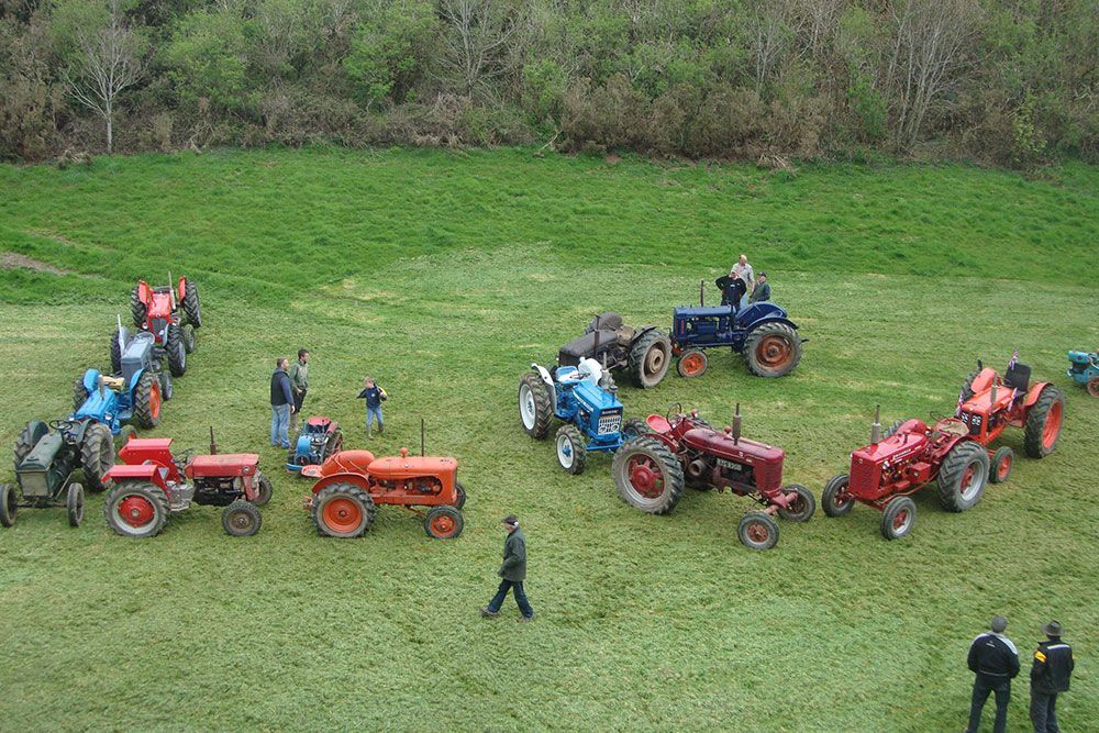 A group of tractors are parked in a grassy field.