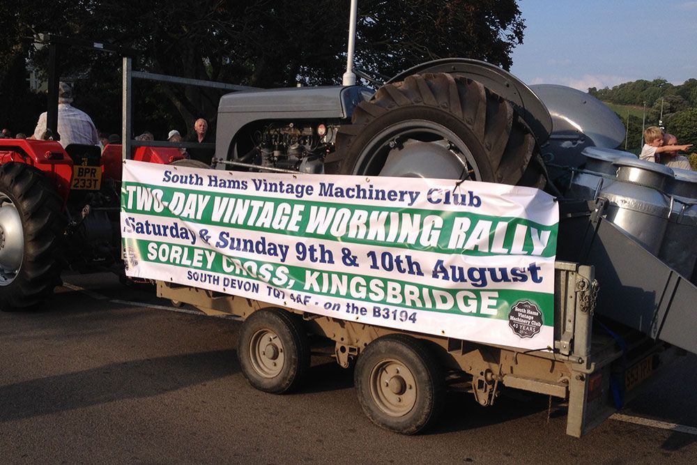A tractor pulling a trailer with a banner that says two day vintage working rally