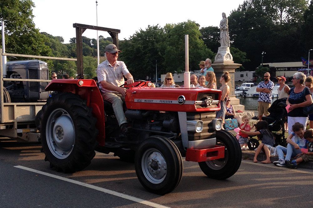 A man is driving a red tractor in a parade