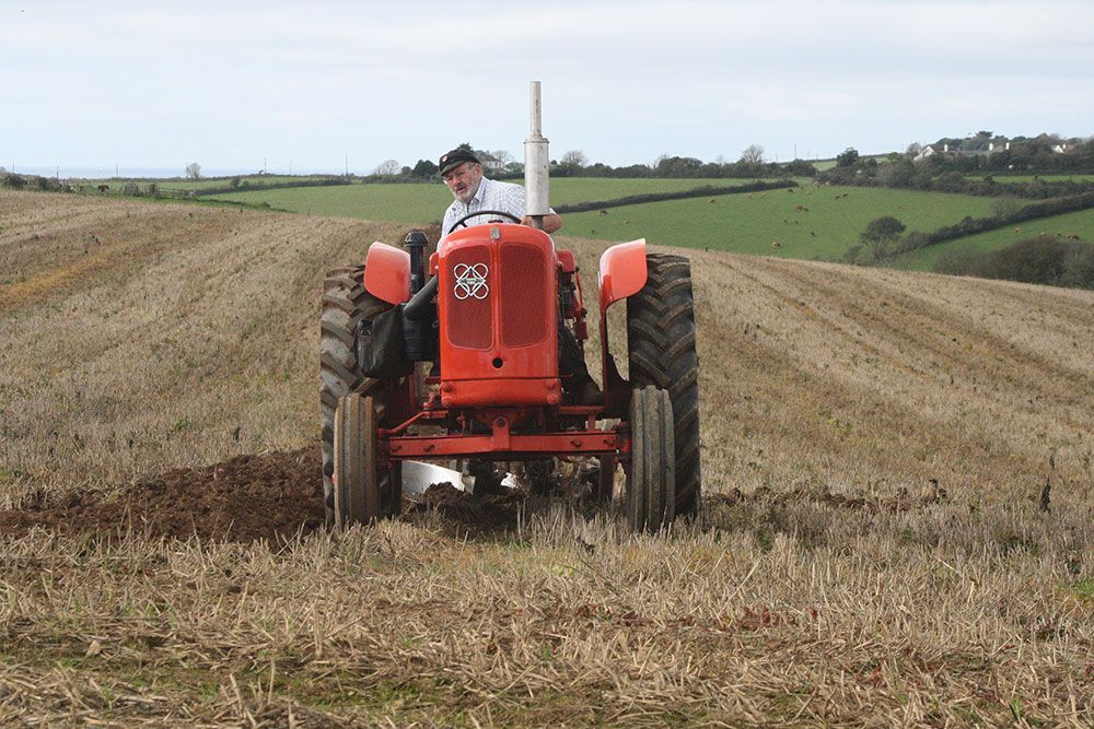 A man is driving a red tractor in a field