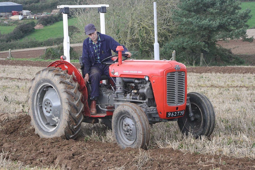 A man is driving a red tractor in a field