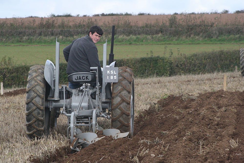 A man is plowing a field with a jack tractor