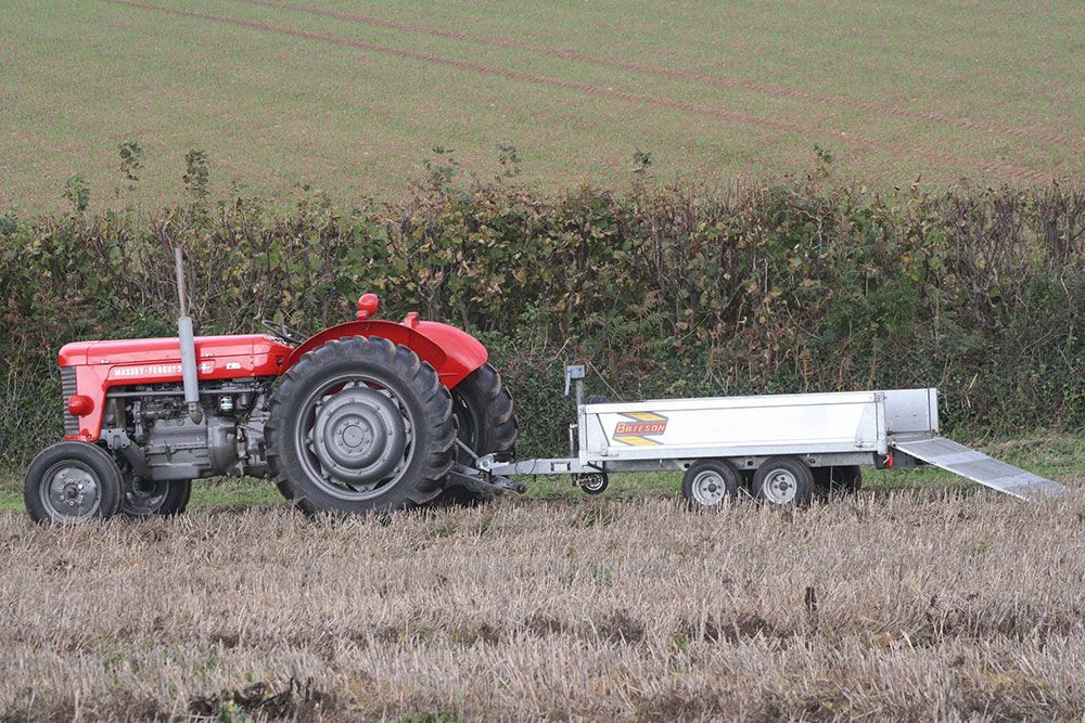 A red tractor is pulling a trailer in a field.