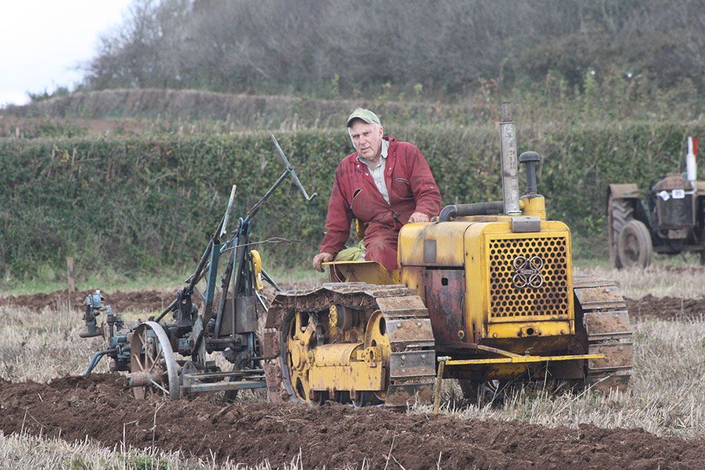 A man is sitting on a yellow tractor in a field.