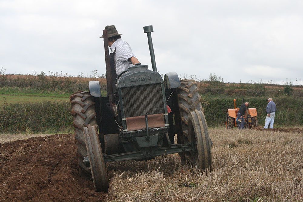 A man is driving an old tractor in a field.