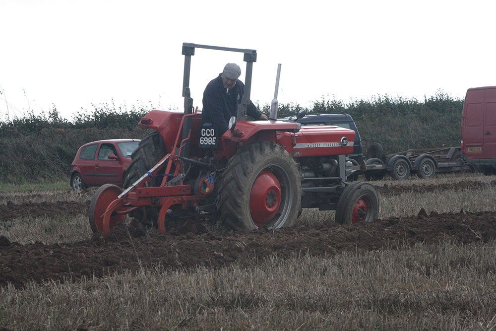 A man is driving a red tractor in a field.