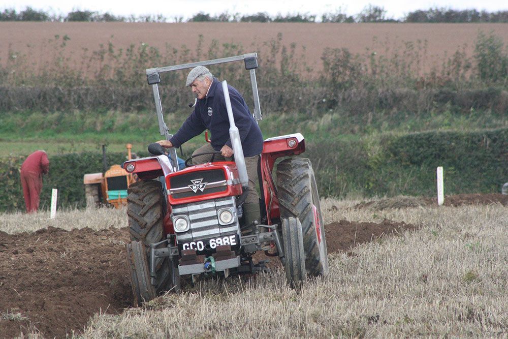 A man is driving a red tractor in a field.