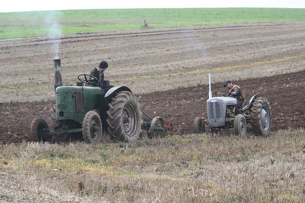 A man is plowing a field with two tractors.