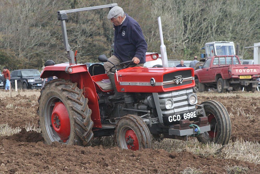 A man is driving a red tractor in a field