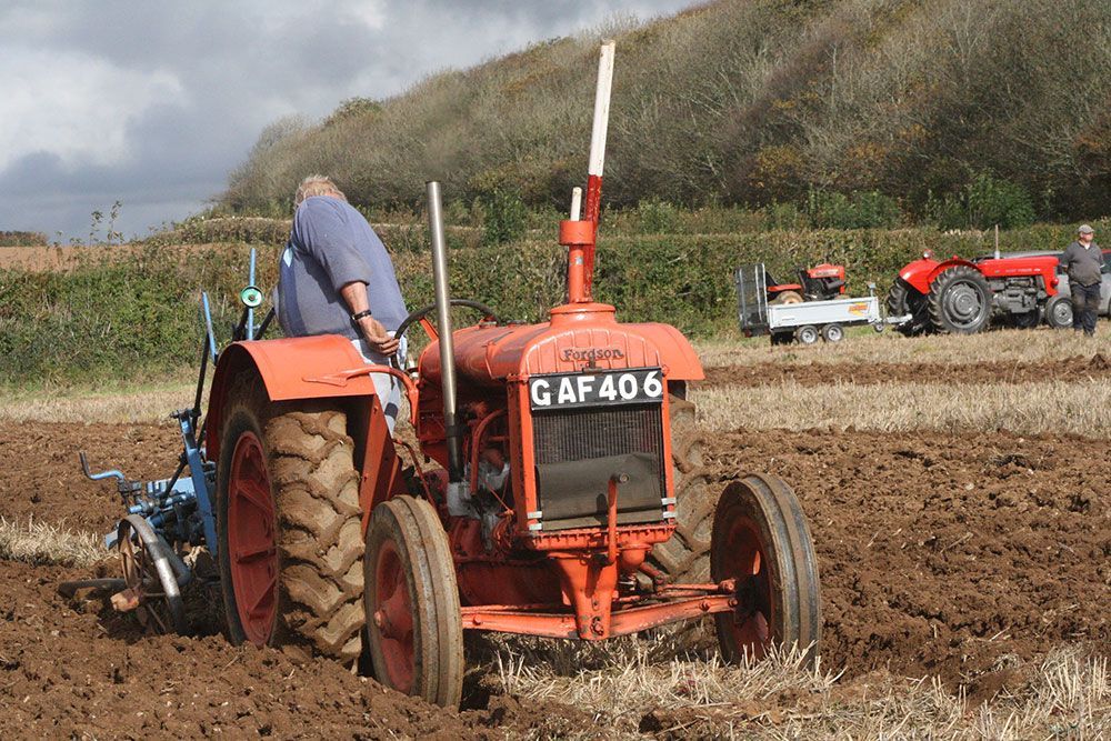 A man is driving a red tractor with gaf406 on the back