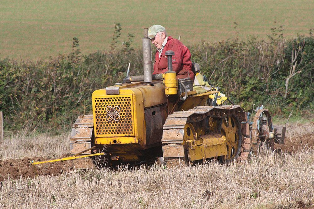 A man is driving a yellow tractor in a field.