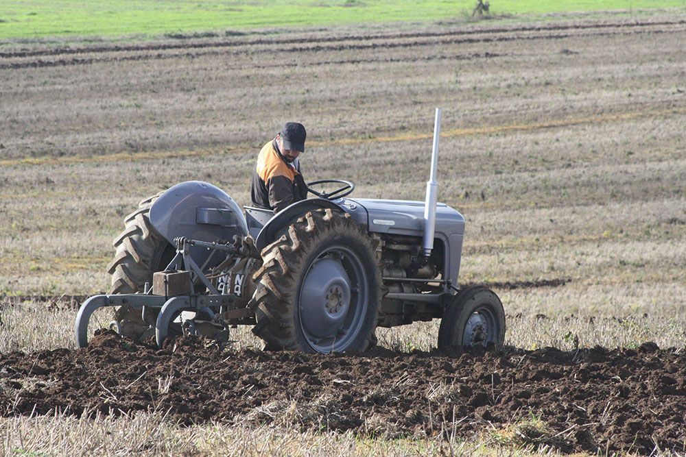 A man is plowing a field with an old tractor