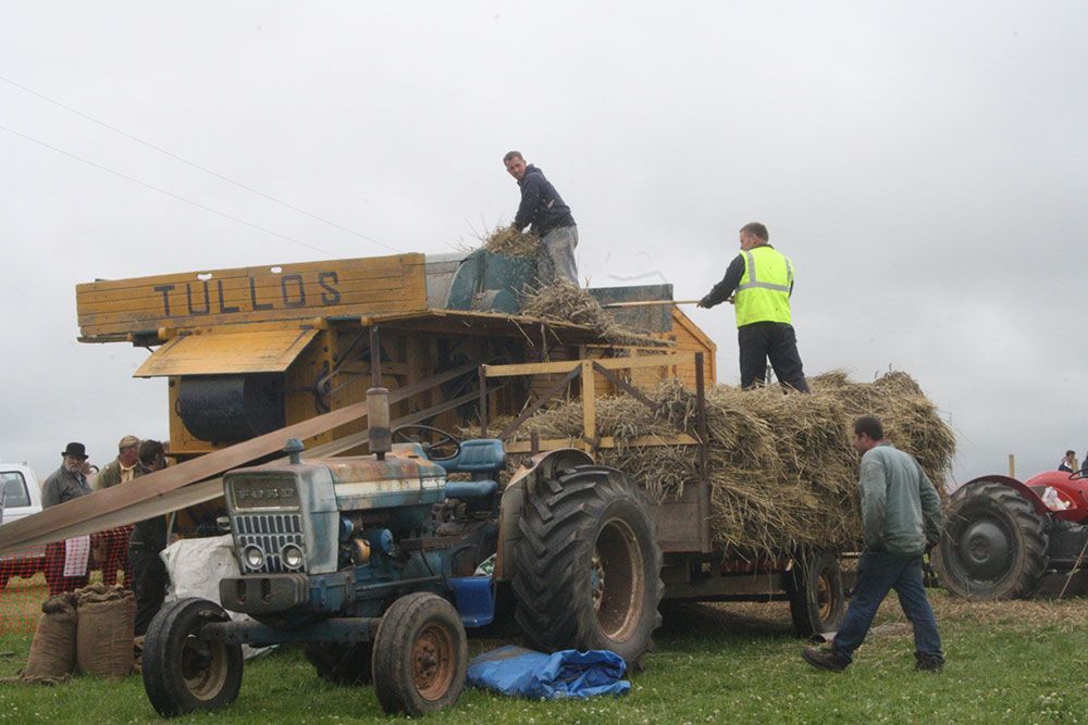 A group of people are working on a tractor that says tullos