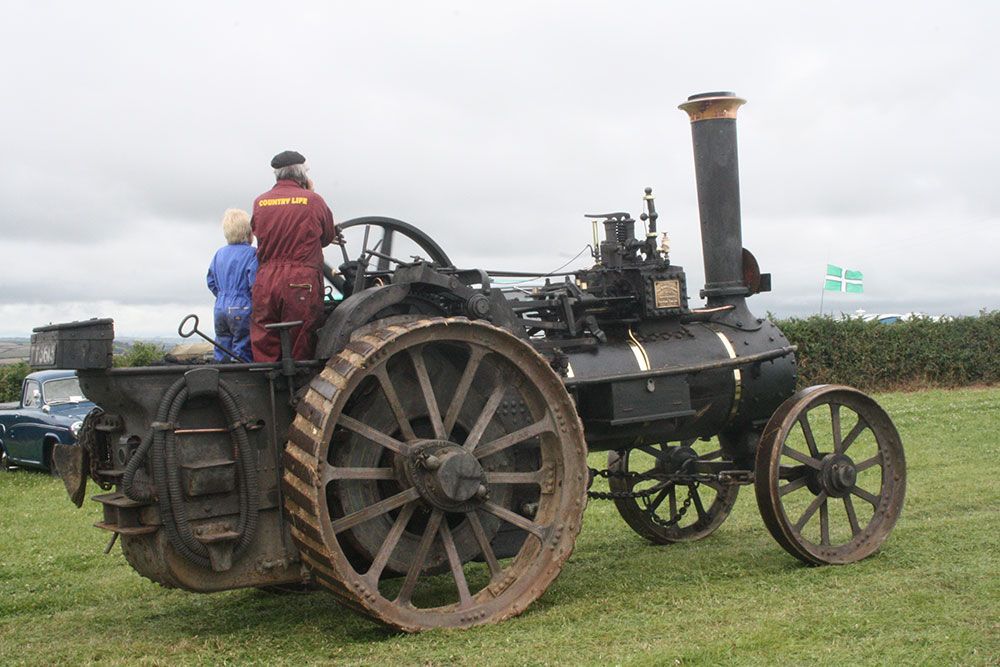 A man and woman are looking at an old tractor in a field.