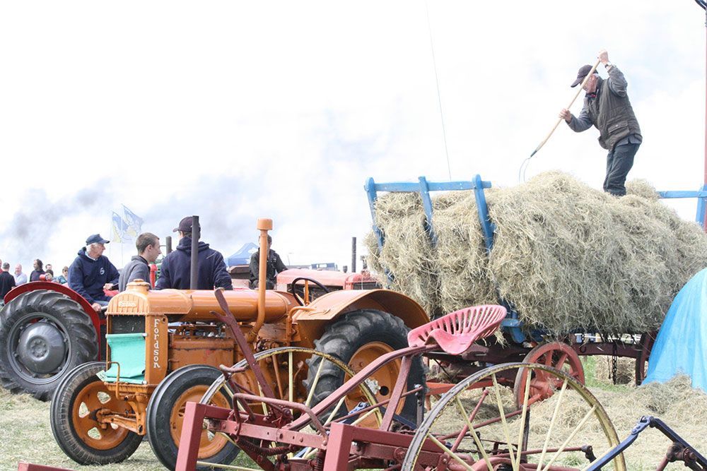 A man is standing on top of a pile of hay.