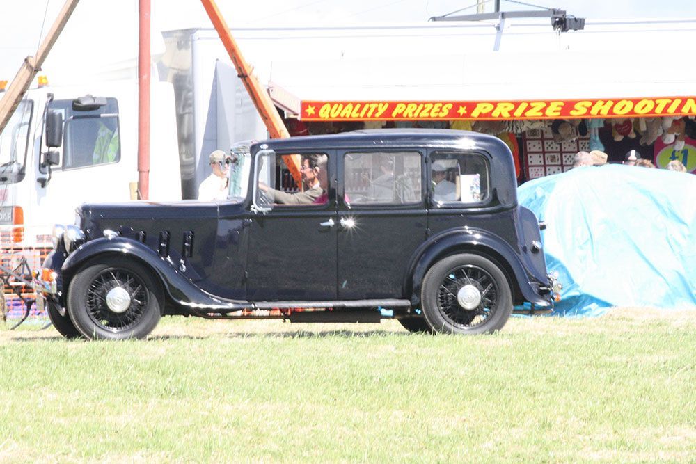 An old black car is parked in front of a prize booth