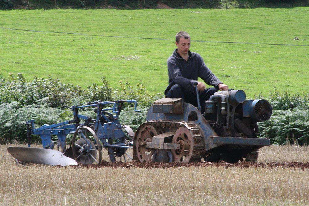 A man is driving an old tractor in a field.