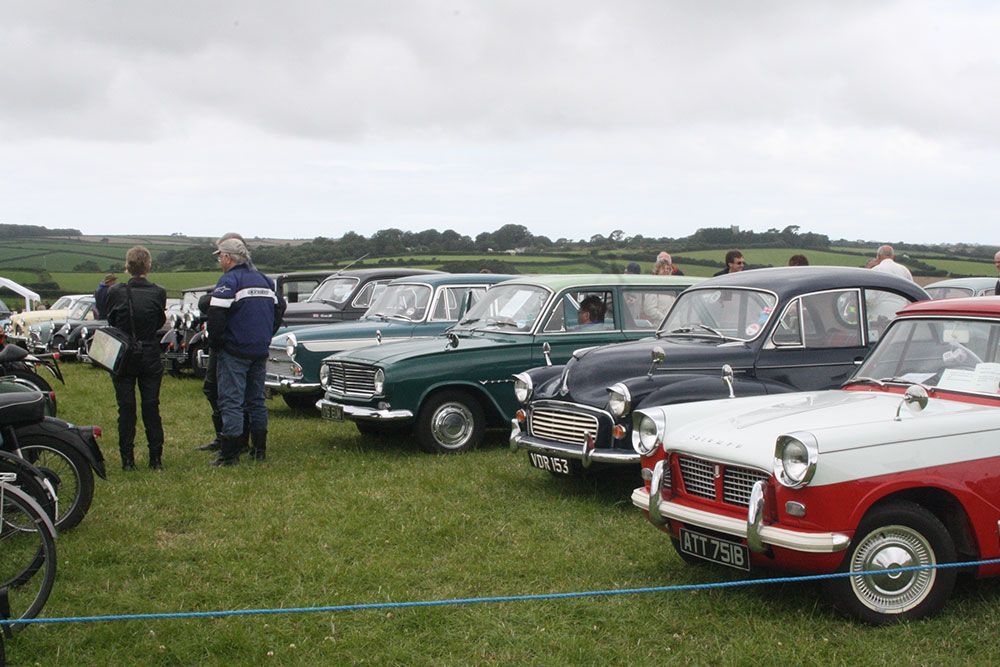 A row of old cars are parked in a grassy field.