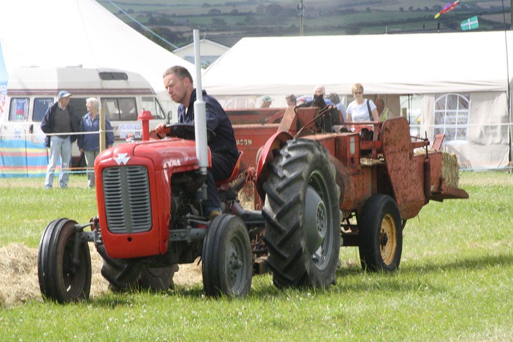 A man is driving a red tractor in a field