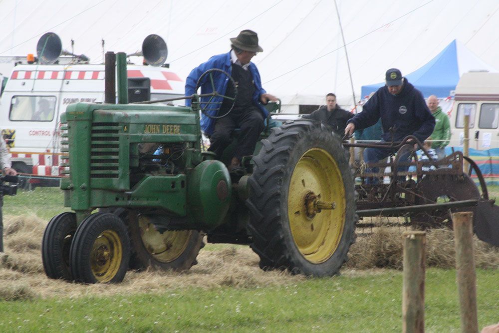 A man is riding a john deere tractor in a field