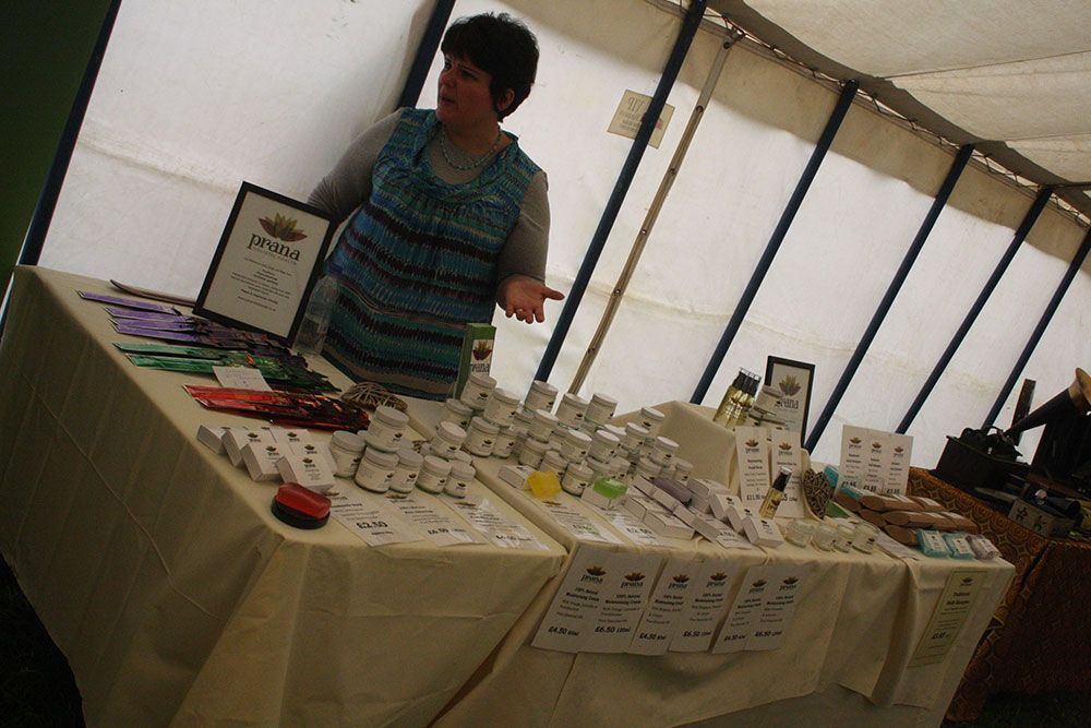 A woman stands behind a table with a sign that says ' witch ' on it