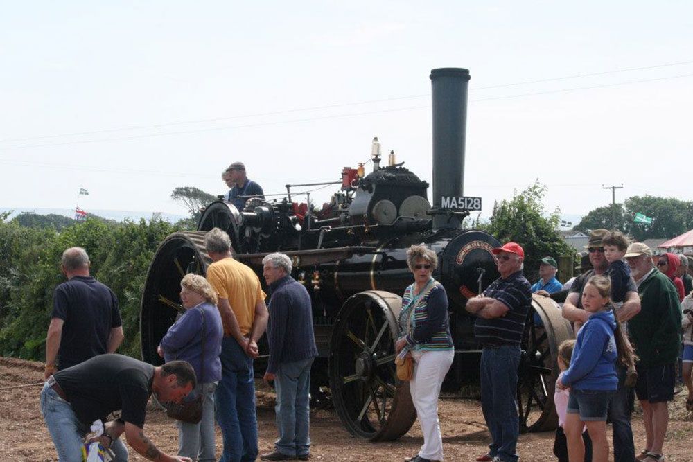A group of people are standing in front of a steam engine that says mass