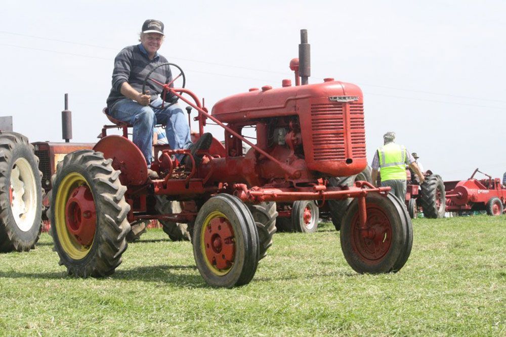 A man is sitting on a red tractor in a field