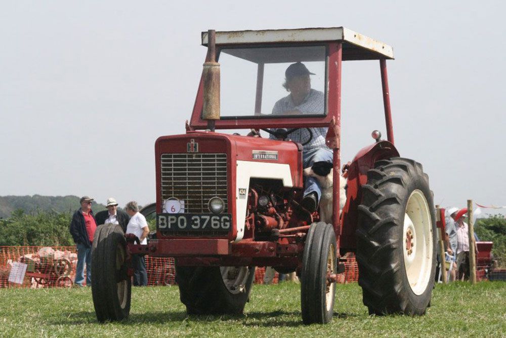 A man is driving a red tractor with the license plate bpo 376g