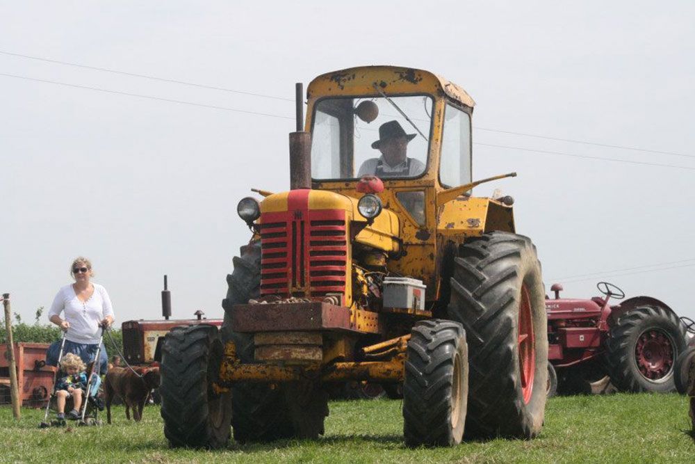 A man is driving a yellow and red tractor in a field.