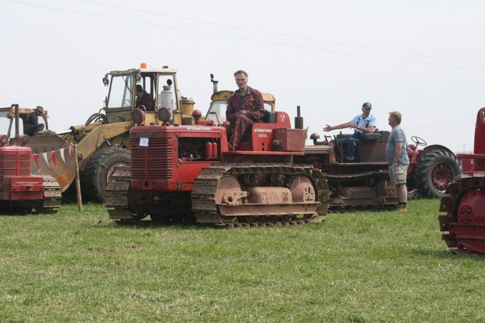 A group of tractors are parked in a grassy field.