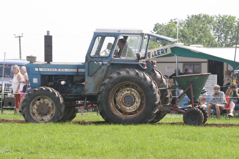 A blue tractor is parked in a grassy field.
