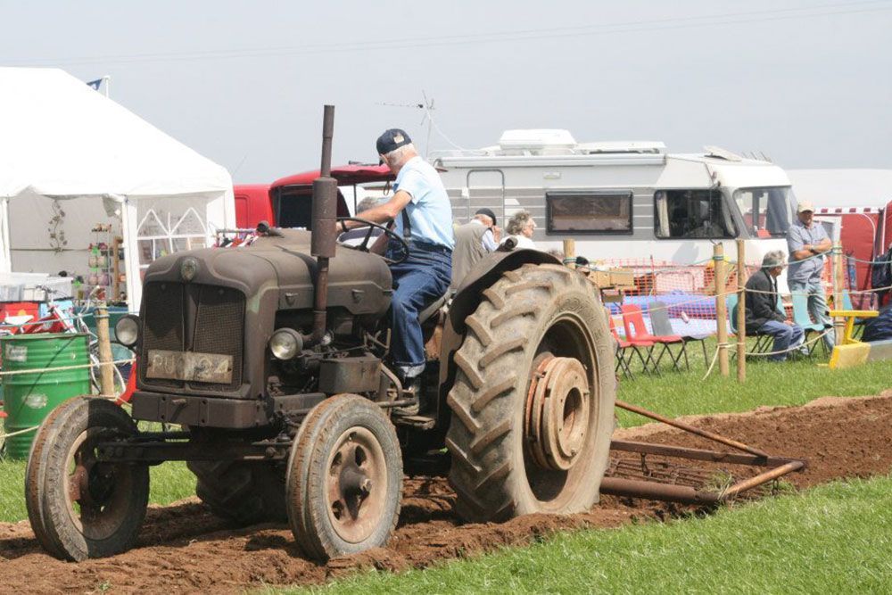 A man is driving an old tractor in a field