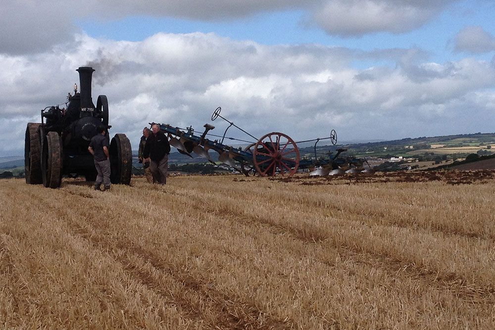 A tractor is plowing a field with a plow attached to it