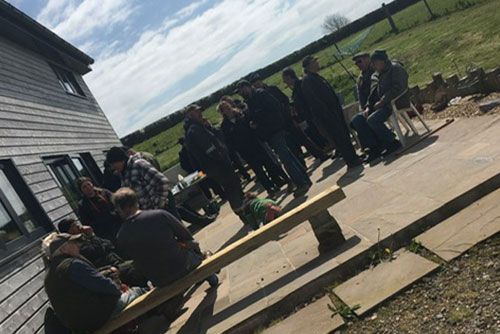 A group of people are sitting on benches outside of a building.
