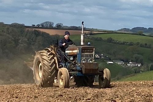 A man is driving a tractor in a field.