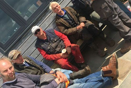 A group of men are sitting on a bench in front of a building.