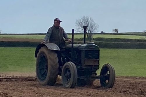 A man is driving an old tractor in a field.