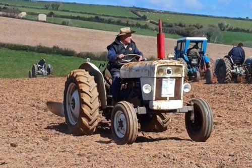 A man is driving an old tractor in a field