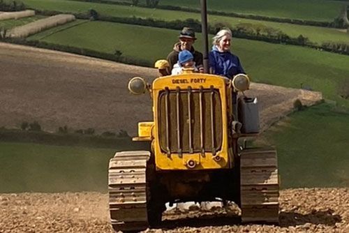 A group of people are riding on a yellow tractor in a field.