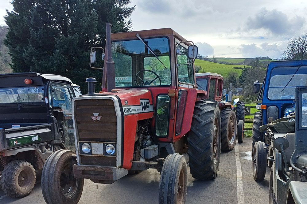 A row of tractors are parked on the side of the road