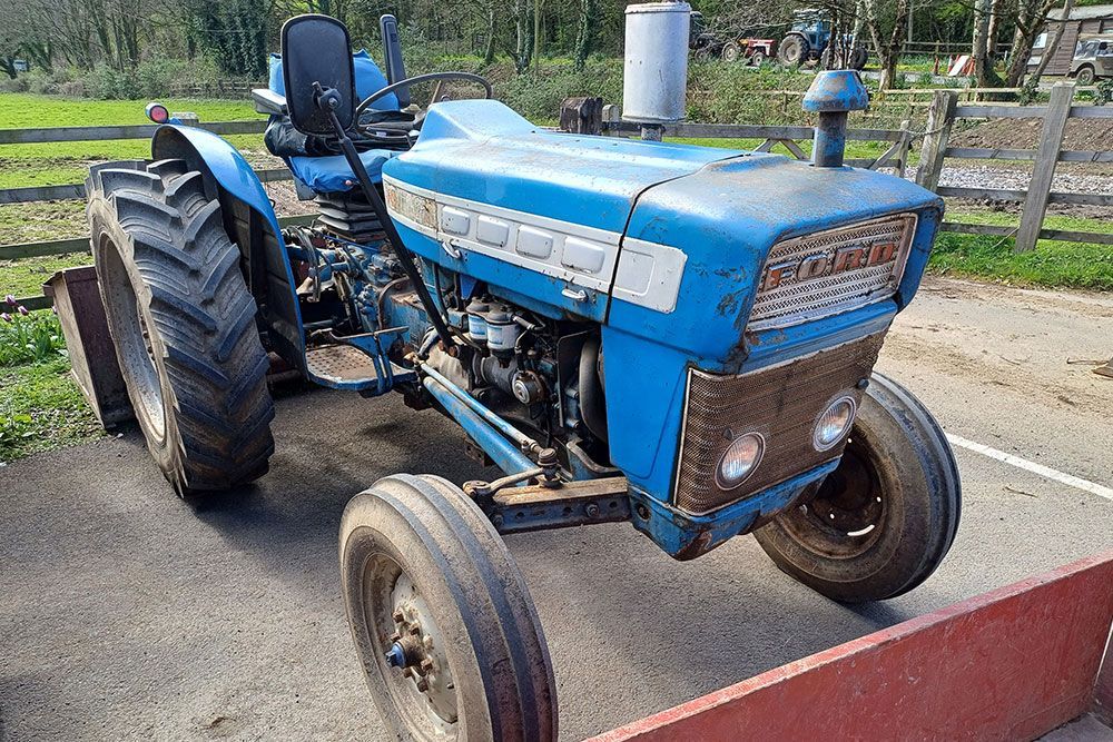 A blue tractor is parked on the side of the road.